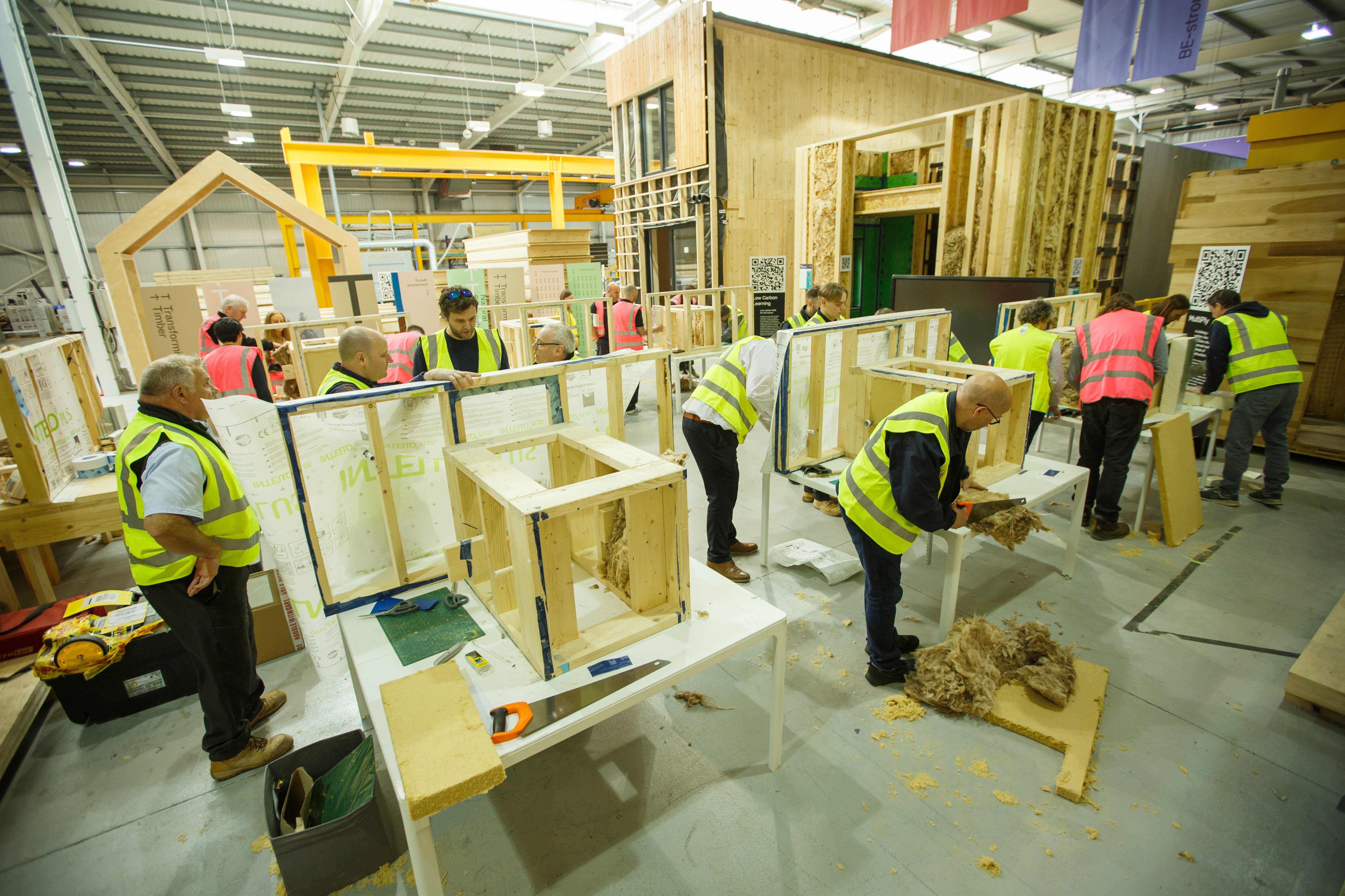 People taping and installing insulation on training rigs in factory.