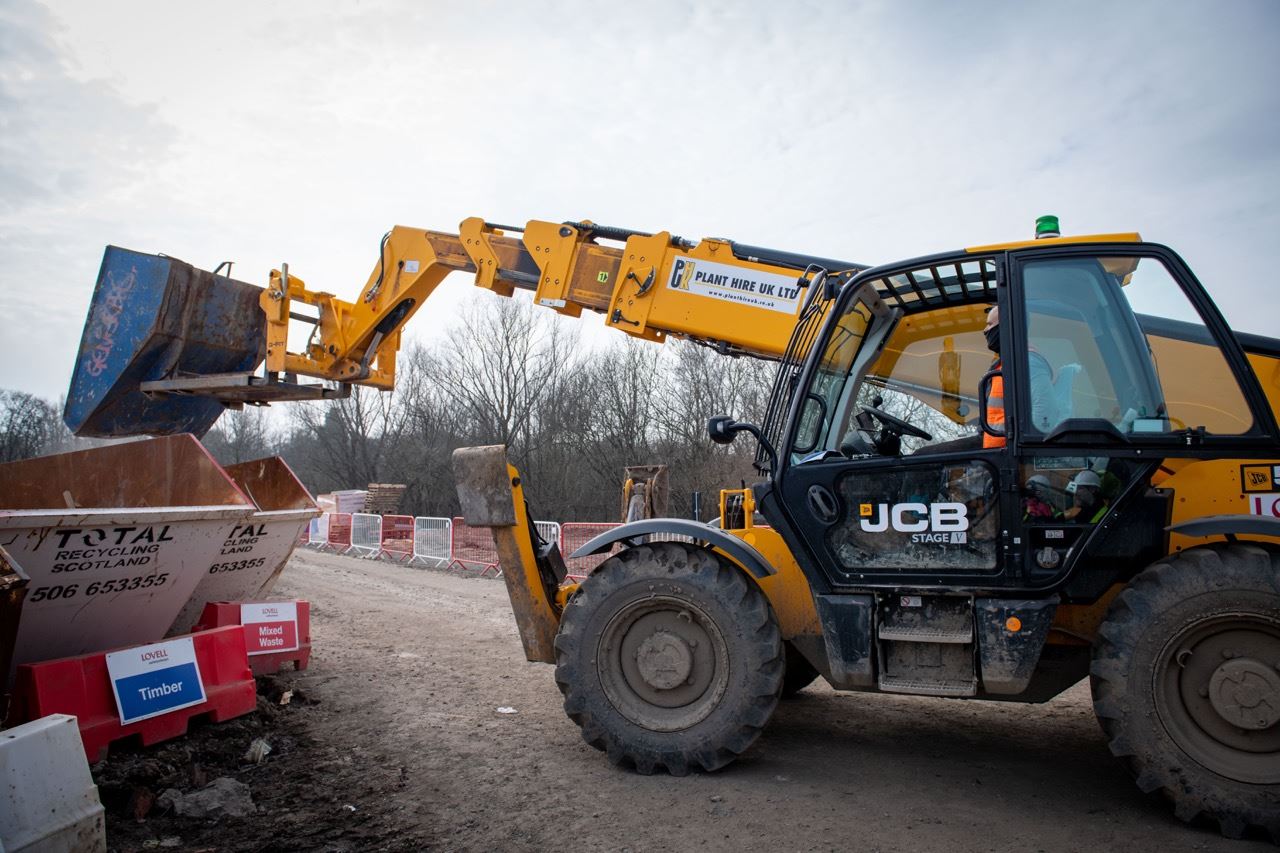 Heavy machinery offloading waste into skip