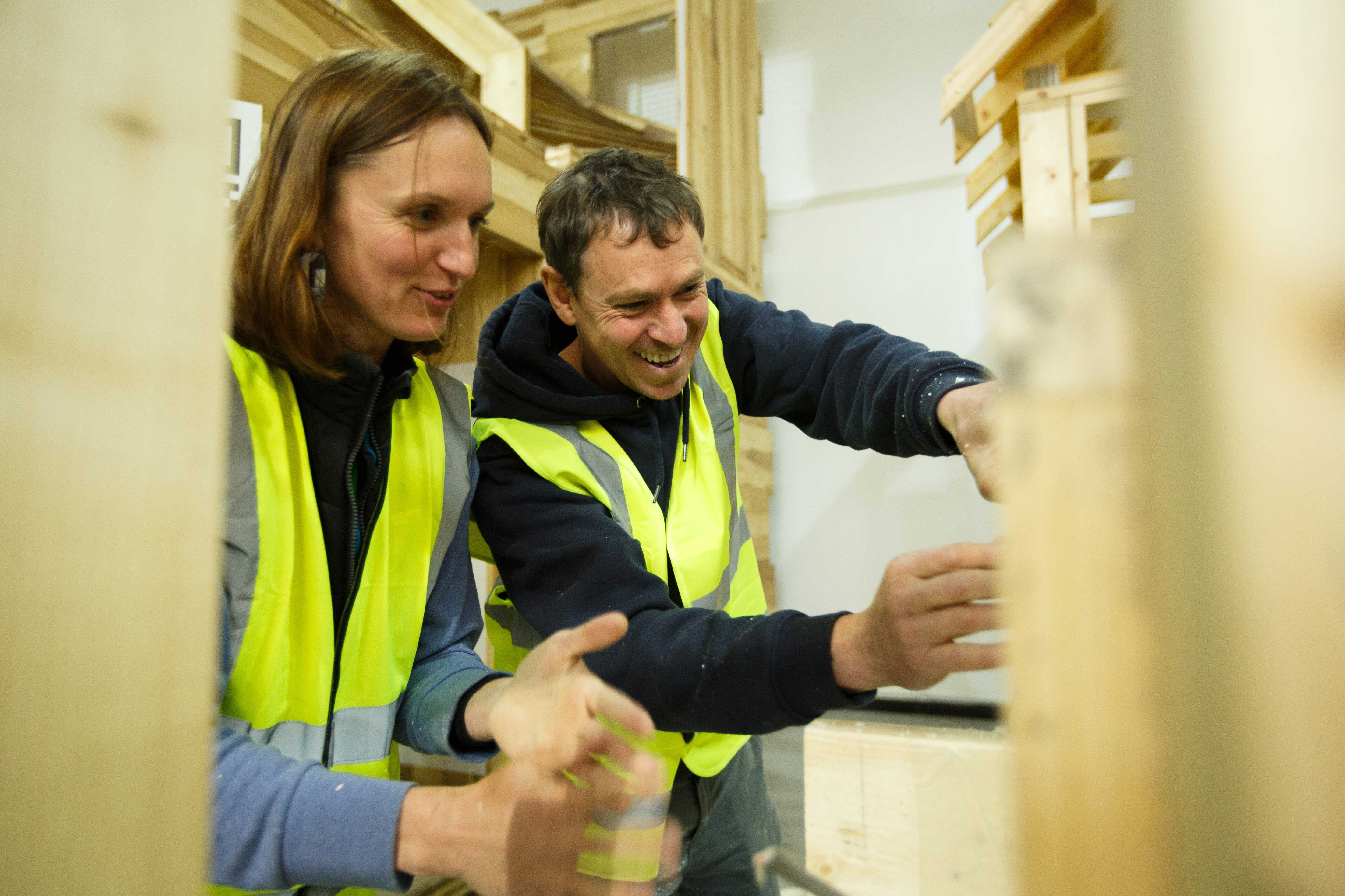 Man and woman smiling while installing insulation